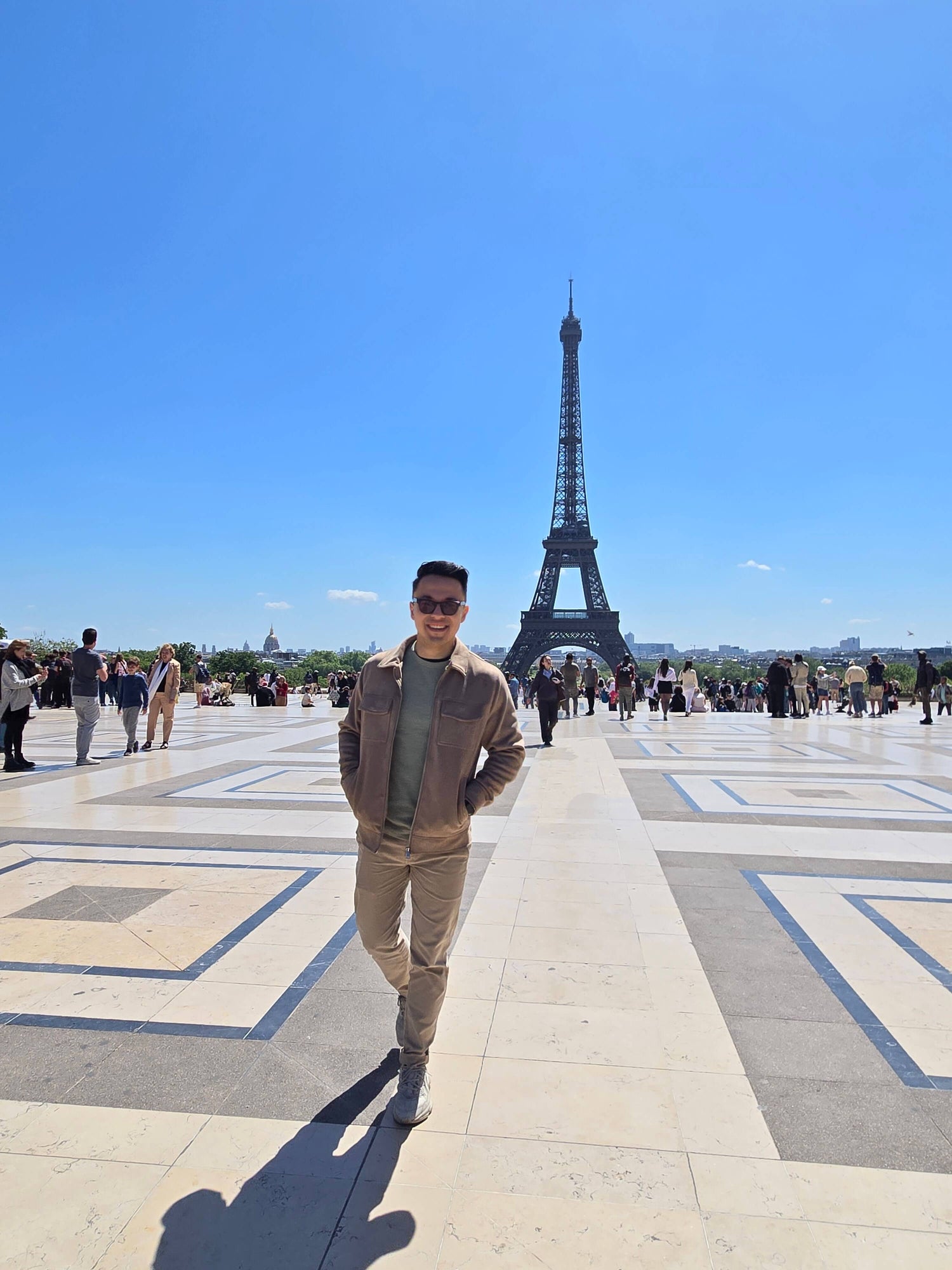 Person standing in front of the Eiffel Tower on a sunny day