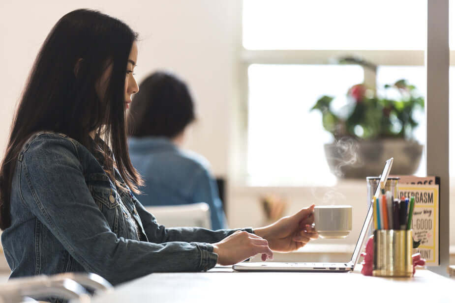 A person sitting at a table with a cup of coffee, engaged in work or studying.