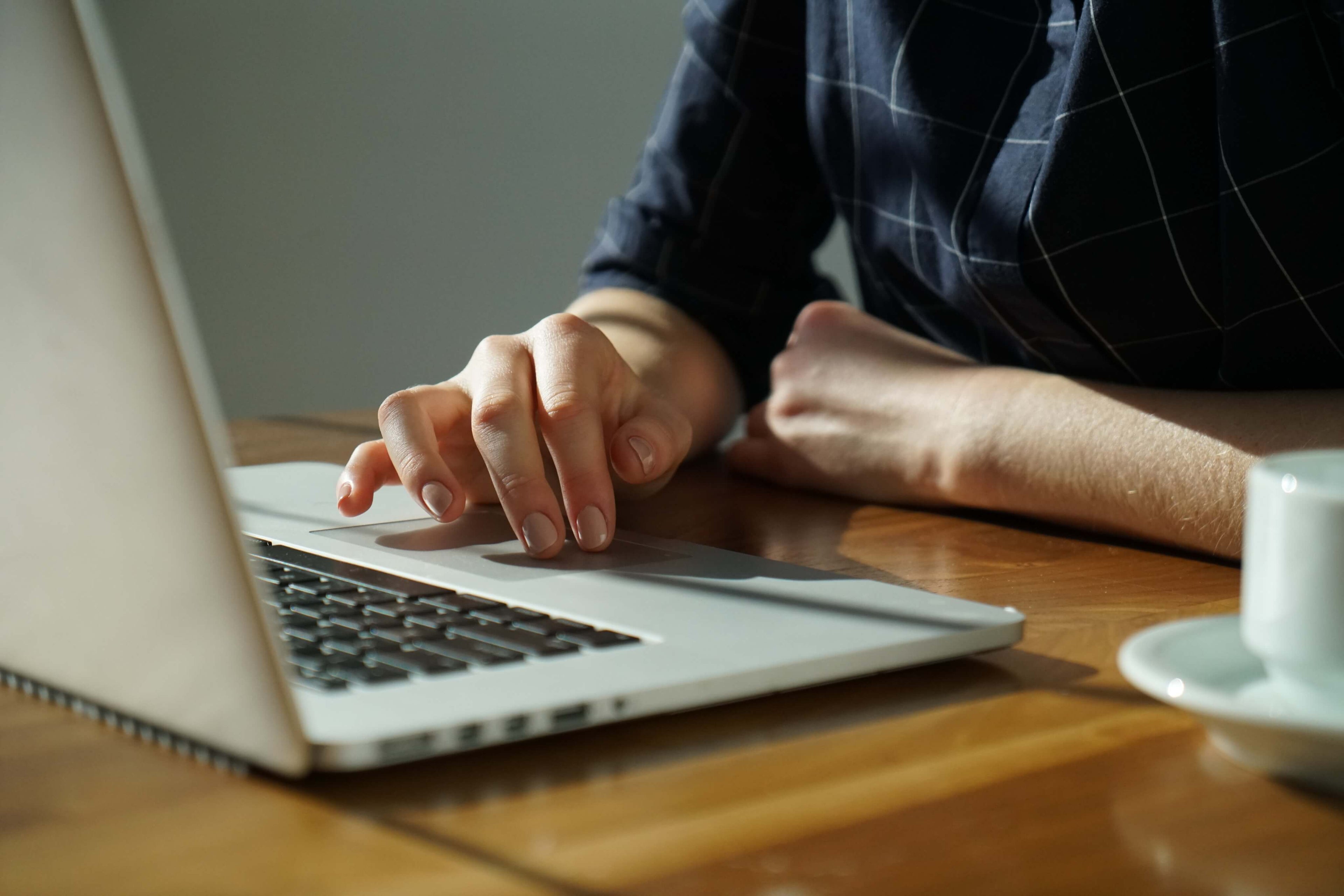 A person using a laptop, hands on the keyboard, typing and navigating with their fingers.