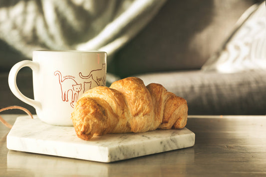 Freshly baked croissant and coffee on a marble plate.