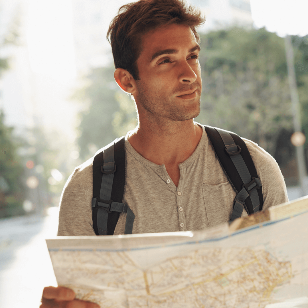 A smiling guy with a backpack confidently holding a city map, navigating his way with a sense of adventure.