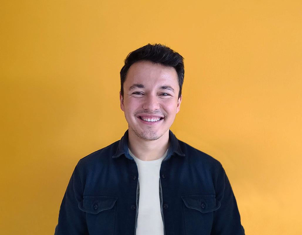 Confident French teacher smiling warmly against a bright yellow background.